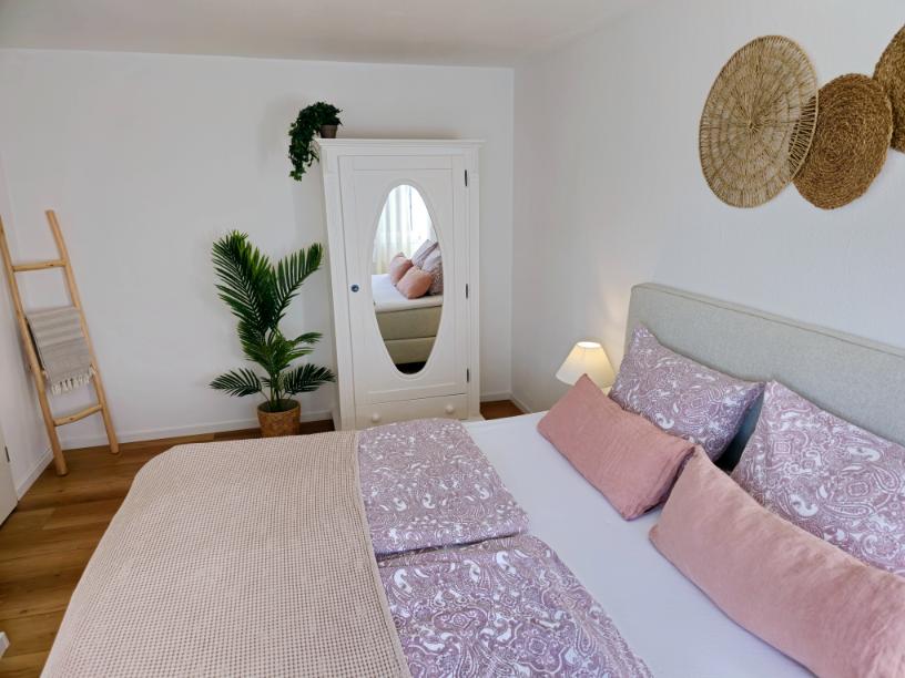 Schlafzimmer mit Doppelbett, Nachttischen und heller Fensterfront in der Ferienwohnung.