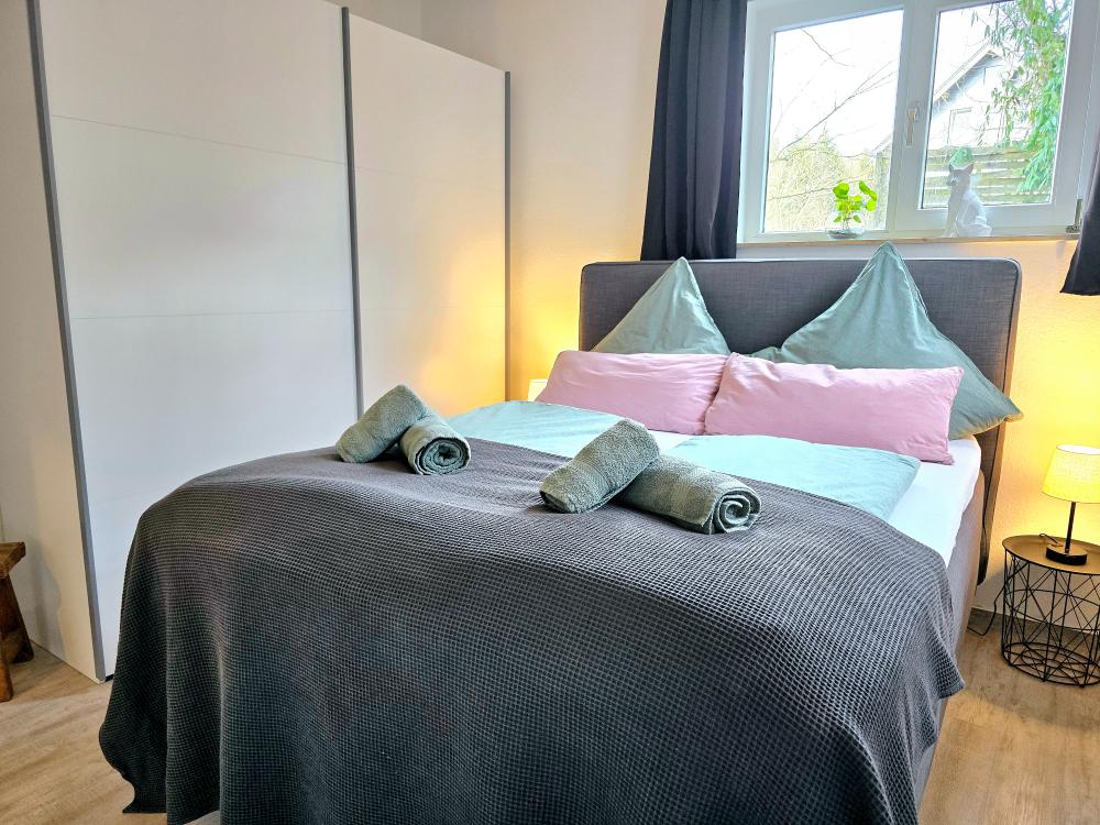 Schlafzimmer mit Dekokissen, Leselampe und ruhiger Atmosphäre.