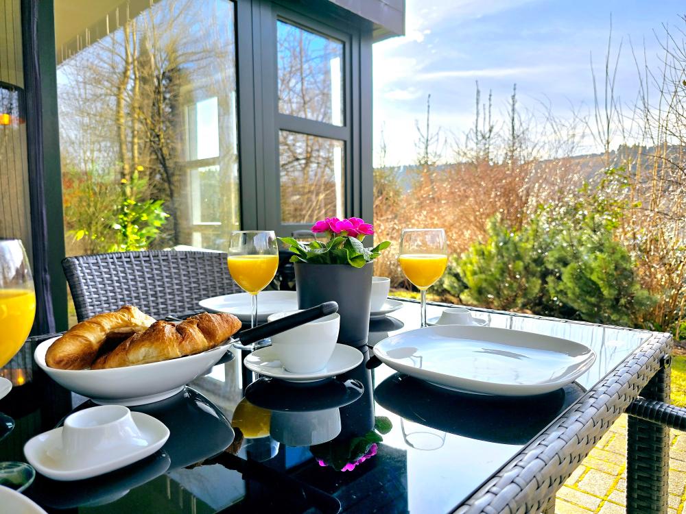 Balkon mit Tisch, Stühlen und Sonnenschirm an der Ferienwohnung in Winterberg.