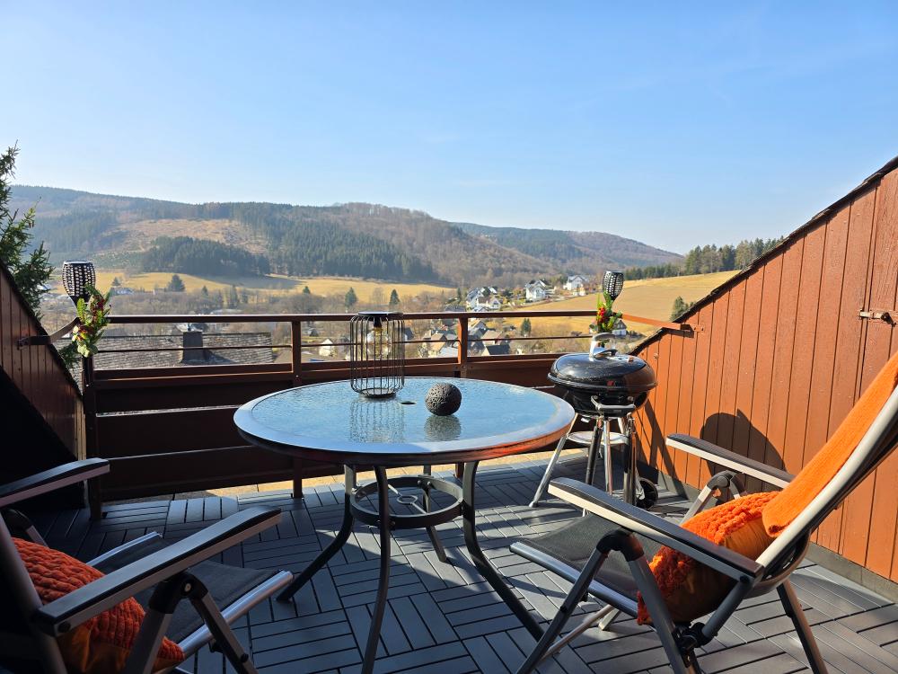 Balkon mit Tisch, Stühlen und Sonnenschirm an der Ferienwohnung in Winterberg.