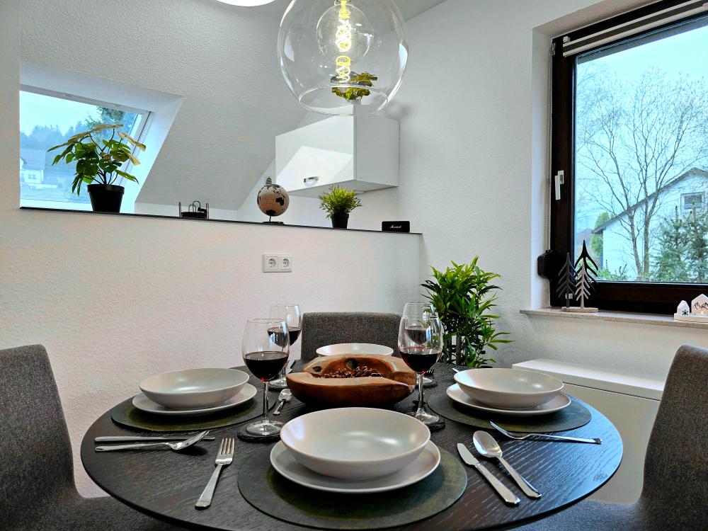 Offener Essbereich mit Tisch, Stühlen und Verbindung zur Küche in der Ferienwohnung Tannenherz.