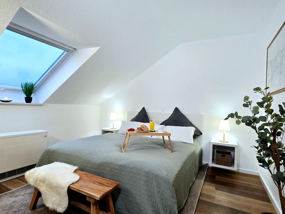 Schlafzimmer mit Doppelbett, Nachttischen und heller Fensterfront in der Ferienwohnung.