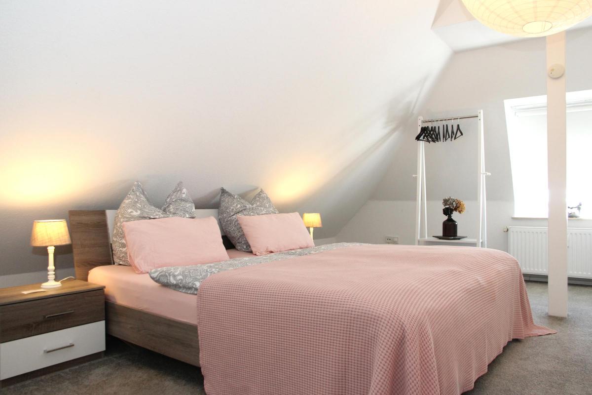 Schlafzimmer mit Dekokissen, Leselampe und ruhiger Atmosphäre.