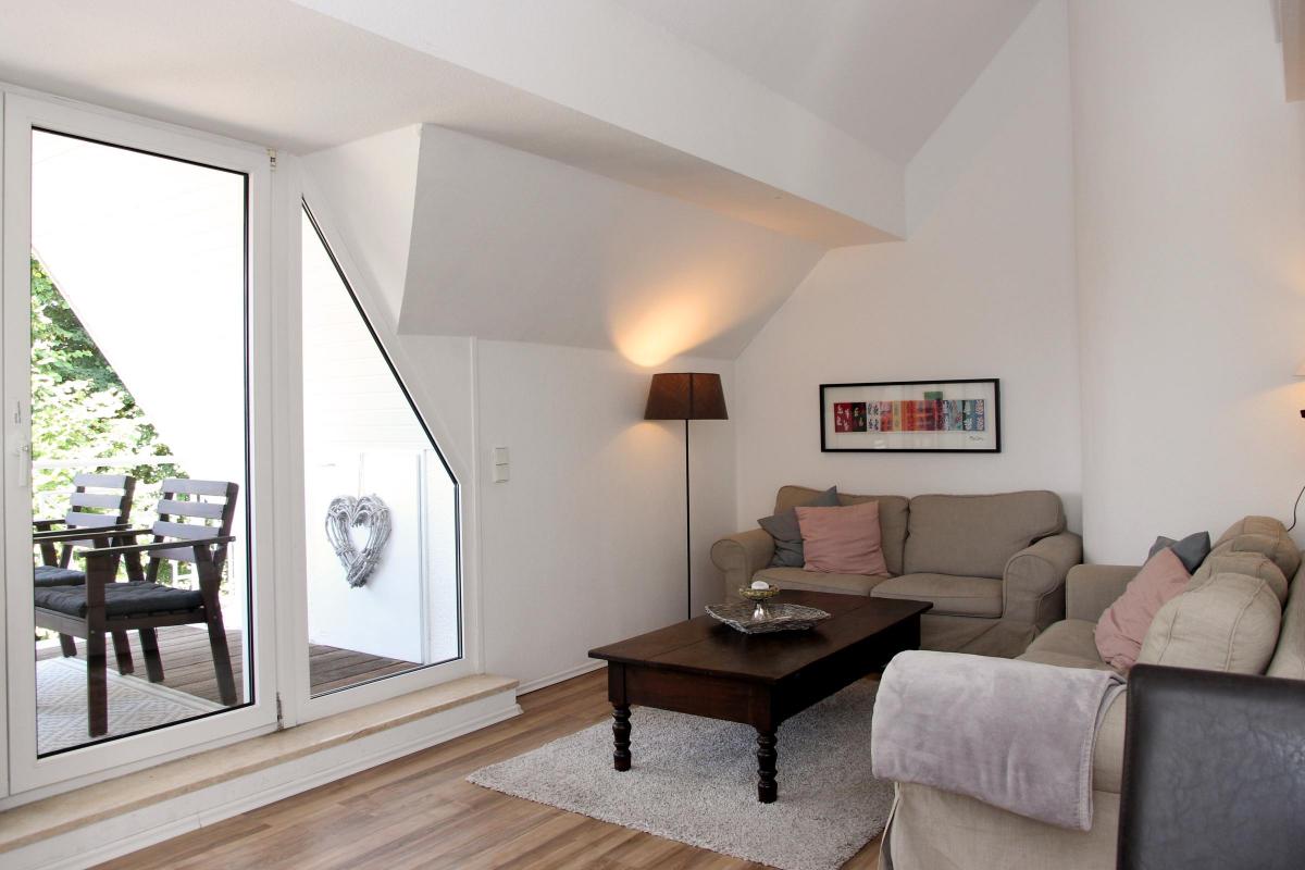 Wohnzimmer der Ferienwohnung am Möhnesee mit Fensterfront, Sofa und hochwertigem Vinylboden.