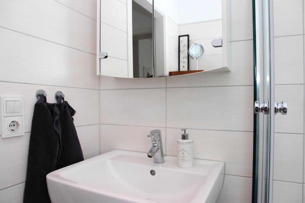 Waschbecken, Dusche und Handtuchhalter im Bad der Ferienwohnung.